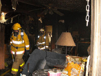 Picture of two SPCFPD firefighters in bunker gear in burnt structure.